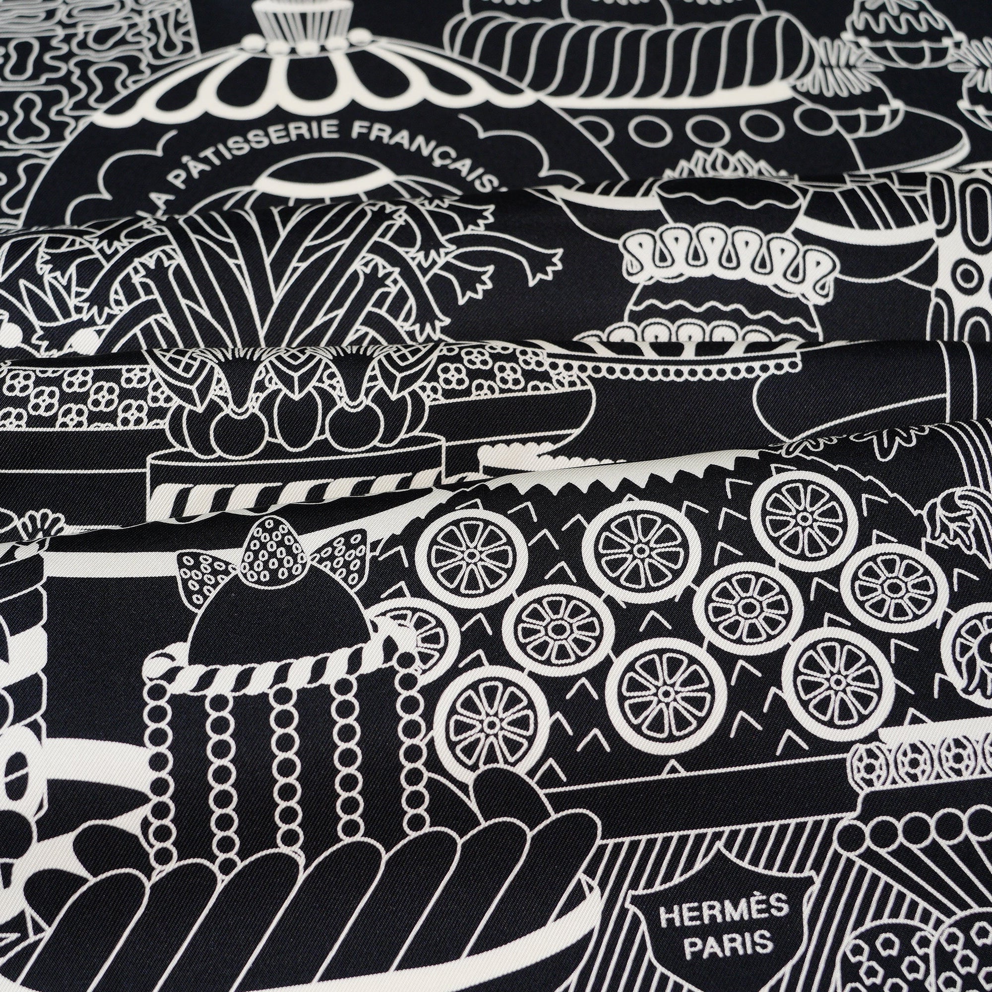 Gros plan sur le cartouche "La Pâtisserie Française" et la signature Hermès Paris sur soie noire.