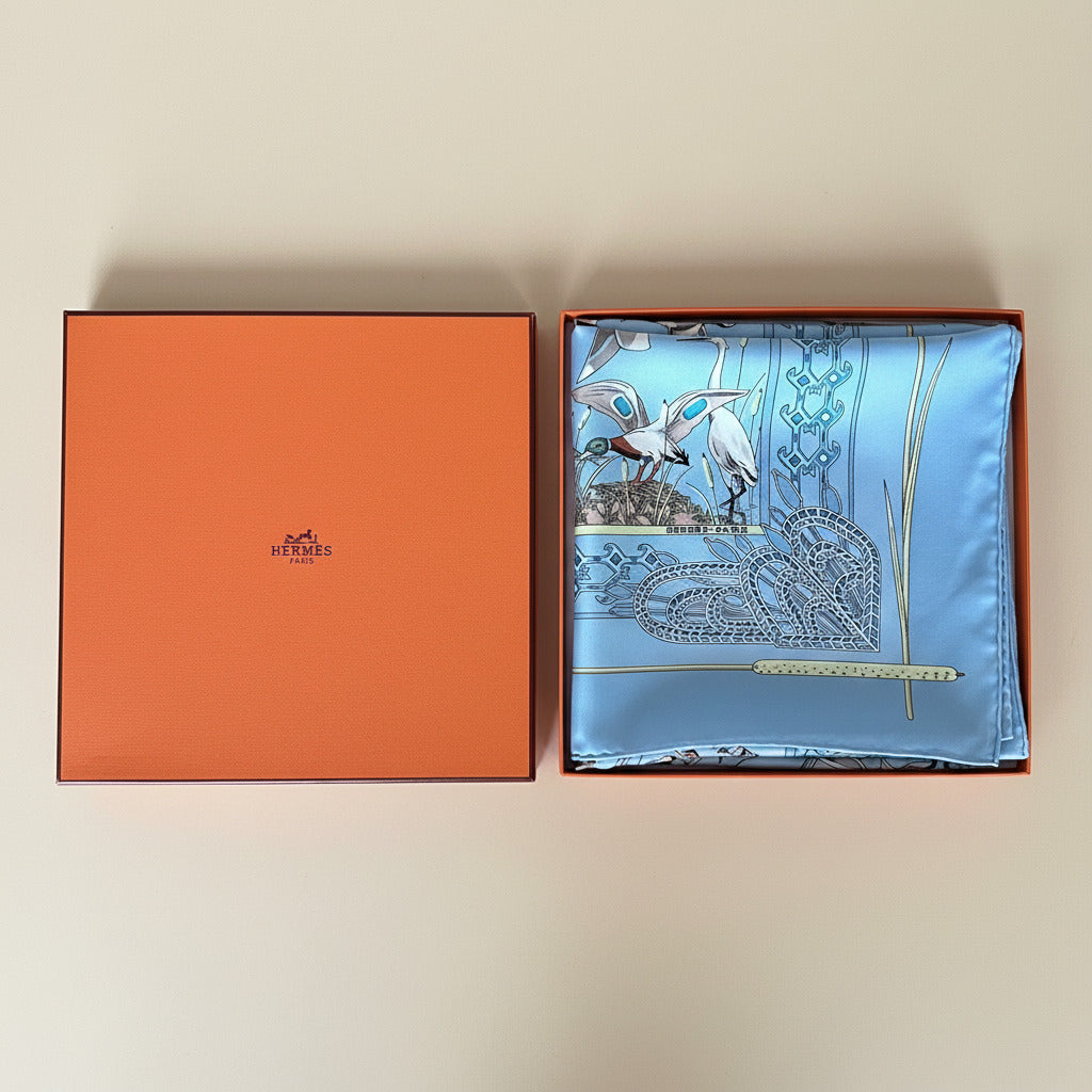 Boîte orange Hermès et foulard en soie bleu plié.