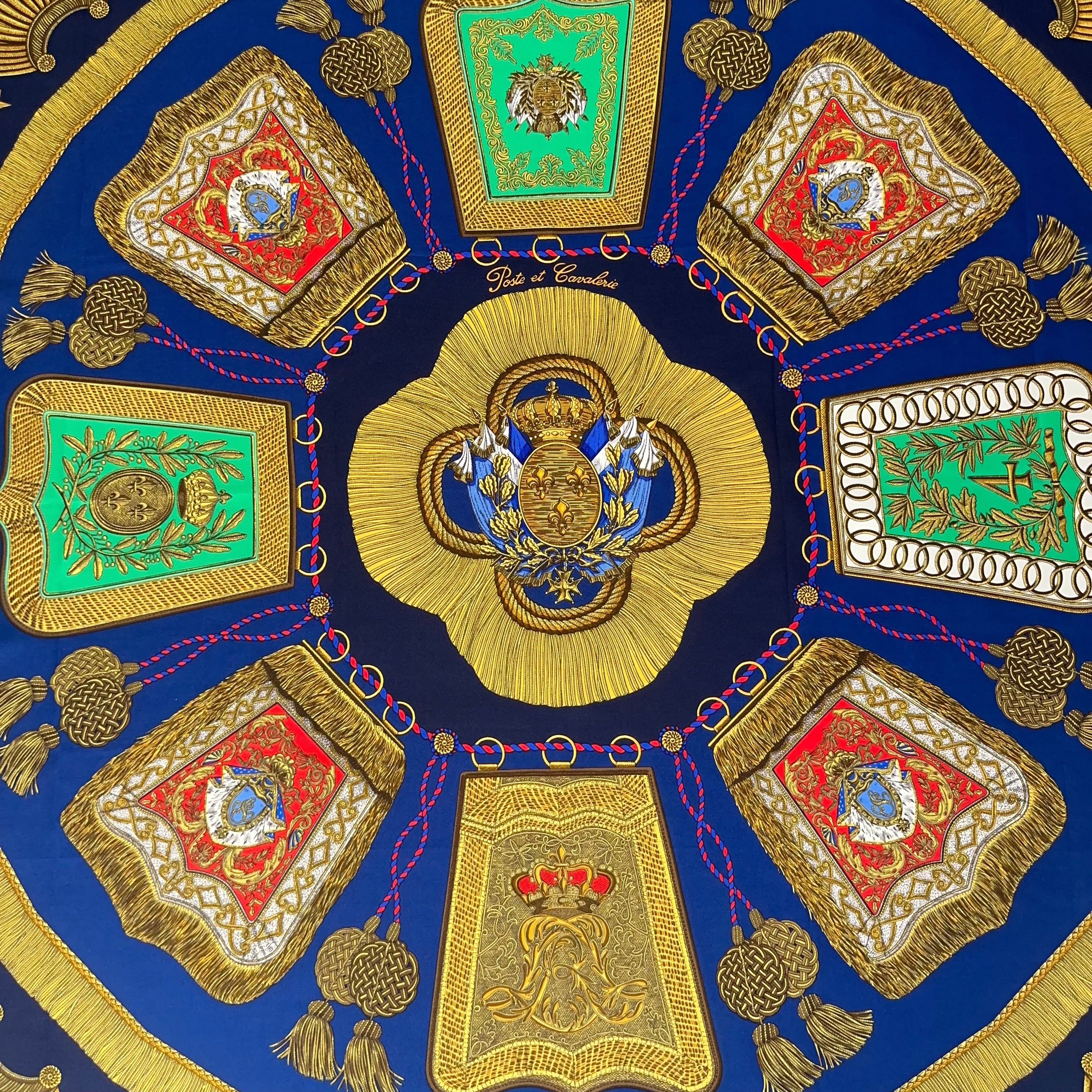 Gros plan sur le motif central : armoiries royales avec fleurs de lys sur fond or, entourées de cordages bleus et rouges sur soie marine.