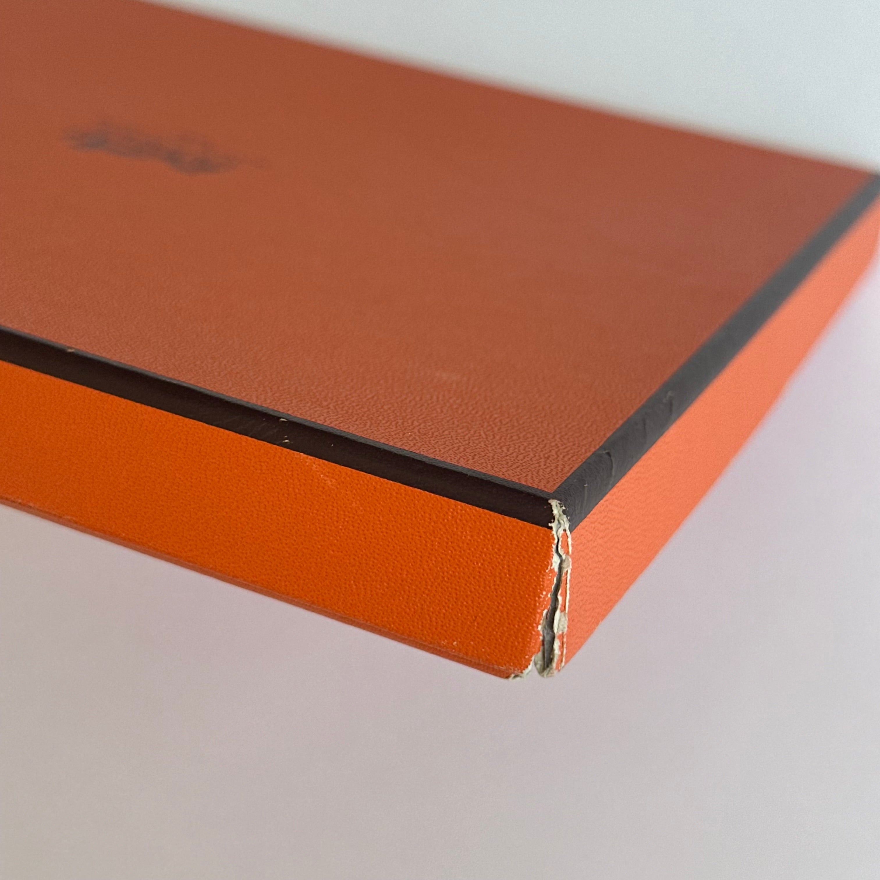 Détail montrant un coin abîmé et déchiré de la boîte orange Hermès vintage fournie avec le foulard.