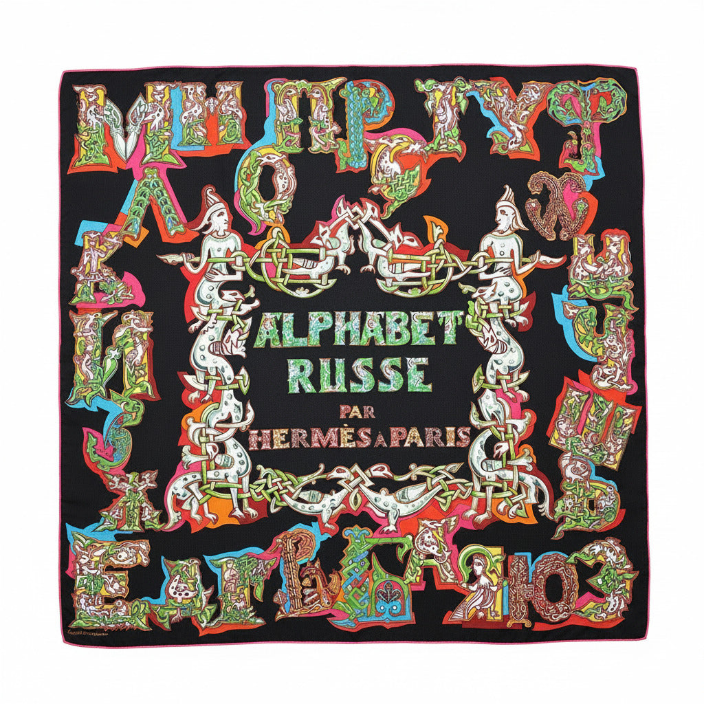 Carré Hermès Alphabet Russe – Vue complète : foulard Hermès 90 cm en soie noire, bord fuchsia, décor typographique inspiré de l’alphabet cyrillique, signé Eugénia Miroshnichenko.